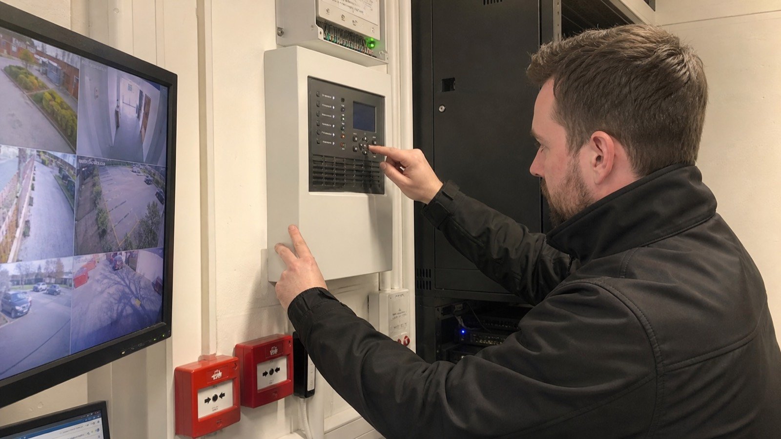 Engineer performing routine fire and security maintenance checks in a commercial plant room